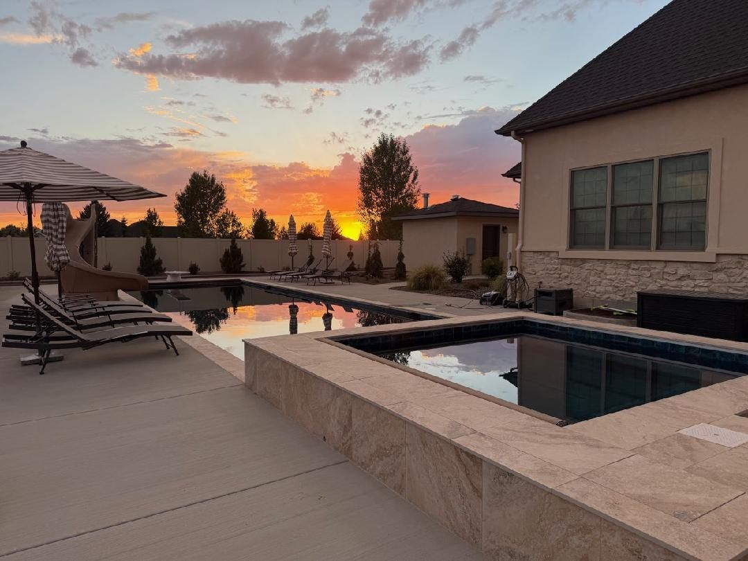 Swimming pool and raised spa at sunset with travertine coping built by Universal Pools Idaho